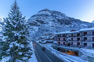 Blick auf Chalets und schneebedeckte Berge in Courmayeur vor dem Morgengrauen im Winter, Courmayeur, Aostatal, italienische Alpen, Italien.