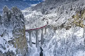 Der Berninabahnzug auf dem Landwasserviadukt im Schnee von Winter, Filisur