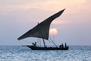Ein Dschungelschiff segelt vor dem untergehenden Sonnenuntergang vor der Stadt Stonetown auf der Insel Zanzibar im Land Tanzanien