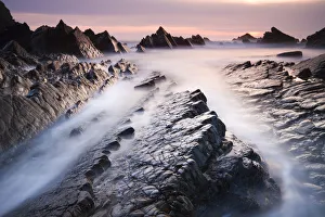 British Seaside Landscape Drucke: Dramatic coastal scenery at sunset, Hartland Quay, Devon, England. Spring (April) 2010