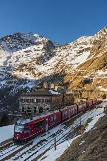 Drucke von Der berühmte Bernina-Express-Rotzug bei der Alp Grüm-Haltestelle, Graubünden, Schweiz Schweiz Drucke: Der berühmte Bernina-Express-Rotzug bei der Alp Grüm Station, Graubünden, Schweiz.