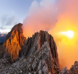 Weniger Sonne, mehr Wolken am Horizont mit dem Berg Roda de Vaei in der Helligkeit und Rücklicht roter Wolken hinter den Felsen