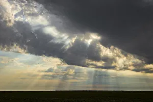 Sonnenstrahlen brechen durch Sturmwolken auf dem Liuwa-Plateau-Nationalpark in Sambia