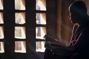 Southeast Asian Spirituality Drucke: A young monk looking out of a window while studying inside a temple, UNESCO, Bagan