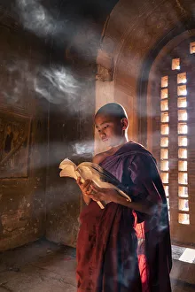 Ein junger Mönch liest vor einem Fenster in einer Tempelhalle der UNESCO im Stadtteil Bagan in der Region Mandalay in Myanmar