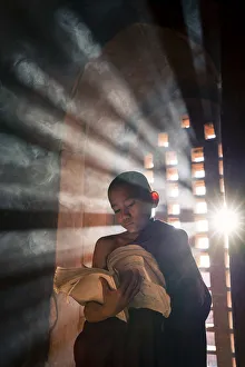 Drucke von Ein junger Mönch liest vor einem Fenster in einer Tempelhalle der UNESCO im Land von Bagan in der Region Mandalay in Myanmar Myanmar Drucke: Ein junger Mönch liest vor einem Fenster im Inneren eines Tempels in der Stadt Bagan auf der Region Mandalay in Myanmar