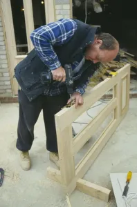 Building Architecture Design Drucke: ARCHITECTURE Construction Carpentry Carpenter using power screwdriver to secure hinge to door