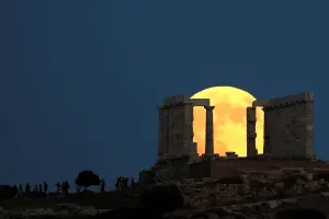 Drucke von Menschen beobachten den vollkommenen Mond am Aufgang hinter dem Tempel des Poseidons vor einem Sonnenuntergang während eines Mondfinsternisses in Kap Sounion, nahe Athen, Griechenland, 27. Juli 2018 Eclipse Drucke: Mondfinsternis in Griechenland