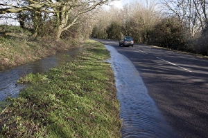 Überfluteter Graben überläuft sich in die Straße bei Aldingbourne nahe Bognor Regis im Südwestengland Februar 2014