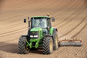 Bilder datiert: Der John Deere Traktor zieht den Bodenpresser hinter sich und rollt das Samenschot im landwirtschaftlichen Feld von