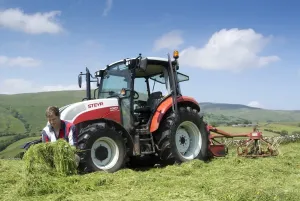 Bilder Datiert 2015: Bauer überprüft Qualität des gemähten Grases neben der Steyr-Traktor mit Teddern in Cumbria