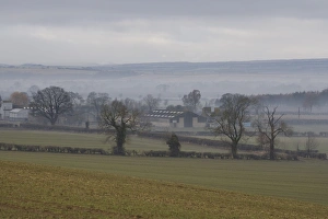 North Yorkshire Moors Landscape Drucke: View of mist over fields and farm buildings