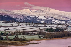 Blick auf schneebedecktes Feld und Hügel zum Sonnenaufgang vom Mynydd Llangorse, See von Llangorse, Nationalpark Brecon Beacons Nord