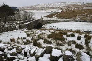 Yorkshire Landscapes Drucke: View of stream flowing through snow covered fields and under stone bridge