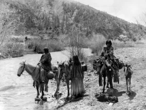 Native American Images Drucke: APACHE GROUP, c1906. Group of Apache men and women, one with a child, with horses