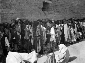 Late 19th Century America Drucke: APACHE RESERVATION, c1899. Line of Apache men, women and children wait for rations