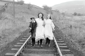 Drucke von Gary Warren, Jenny Agutter und Sally Thomsett lächeln dem Kamera vorwärts als sie entlang der Eisenbahnlinie gehen während des Drehes von The Railway Children Film und Filmplakate: Die Dampfbahn-Kinder (1970)