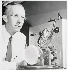 High Voltage Technology Drucke: Dr. Edwin Muller Examining Microscope Display