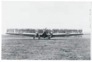 Large Group Of People Drucke: Men Testing a Plane's Wing Rigidity