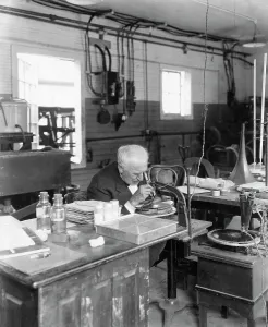 Drucke von Thomas führt ein Experiment im Labor durch Thomas Edison Drucke: Thomases Edisons sieht durch das Mikroskop