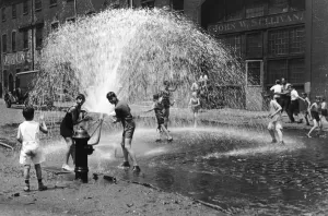 Drucke von Um etwa 1930 spielten eine Gruppe von Kindern im Shorts auf einer Kiesstraße einen Spielplatz am Wasserhahn in einem Straßenbild aus New Yorker Stadt mit Foto von P.L.Sperr / Hulton-Archive/ Getty Bilder Datiert 2019 November: Wasserspender-Hochstimmung