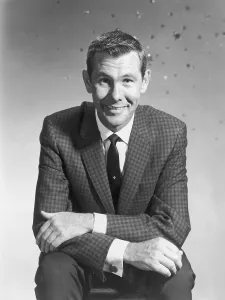 Drucke von Etwa 1955: Bühnenbild von Johnny Carson, einem amerikanischen Komiker und Fernsehshow-Host, der mit gefalteten Armen auf den Knien sitzt und lächelt Zeitloses Fernsehen: Eine visuelle Reise: Johnny Carson