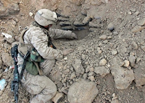 Iraq War Photos Drucke: A combat engineer carefully scoops dirt away from a stack of mortar shells