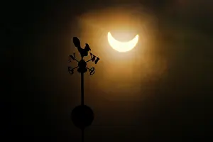 Natural Science Photography Drucke: Partial solar eclipse above silhouette of weather vane, Wroclaw, Poland. 3rd March, 2015