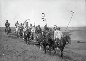 Drucke von Auf dem Kriegsweg - Atsina, 1910. Ein kleiner Band von Männern der Atsinaner auf Pferden mit einigen Stäben und Federn; einer trägt einen Kriegerhut Montana Drucke: Auf dem Kriegsweg - Atsina, 1910 (Kreiszerstatter). Urheber: Edward Sheriff Curtis
