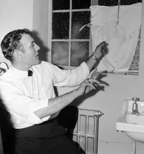 00099 Drucke: Der amerikanische Sänger Carl Perkins weist auf einen zersplitterten Fenster im Vorzimmer des Odeons
