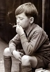 Schlaue Junge raucht eine Zigarette um die Jahr 1950