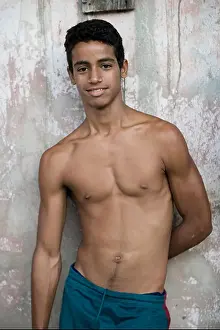 Ein adolescenter Kubaner lehnt sich an eine pastellfarbene Wand in Baracoa.