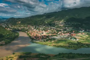 Mtscheta Georgien. Luftaufnahme einer idyllischen Hochlandlandschaft mit blauem Himmel über dem alten Dorf in der grünen Talsenke, wo sich die beiden Flüsse treffen