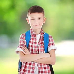 Schöner Junge mit Rucksack auf verschwommener grüner Hintergrund. Schulkonzept.