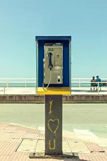 Drucke von Schmutziges und aufgegebenes Telefonhäuschen mit romantischen Graffitis und ein Paar im Hintergrund Straßenkunst Graffiti Drucke: Schmutzig und verlassene Telefonzelle mit romantischen Graffitis und ein Paar im Hintergrund