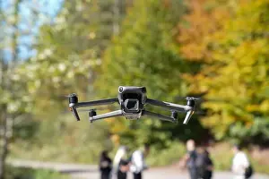 Ein Drohne fliegt über einen See mit Bäumen im Hintergrund