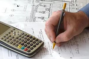 Ingenieur macht auf einem Berechnungssheet Handrechnungen mit einer Taschenrechner am Rande
