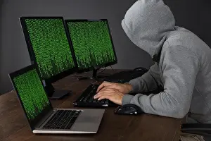 Betrüger am Schreibtisch mit Computern und Binärcode tippen