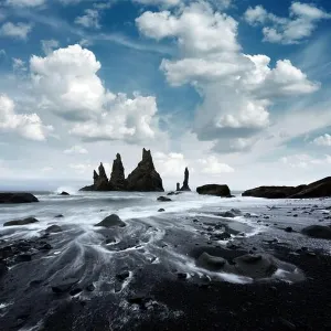 Bewundernde Landschaft mit Basaltschuttformationen Trollsfüße auf der schwarzen Strandung, stürmische Wellen des Ozeans und Wolkenlandschaft. Reykjavík ist nicht im Text enthalten. Die genaue Stadt in Iceland lautet: Vik