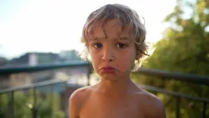 Porträt eines jungen Jungen mit trauriger Miene. Sturmerlebnis eines kleinen männlichen Kindes, das sich außerhalb steht und auf die Kamera schaut. Unglückliches Kind
