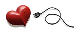 Ein rotes Herz mit einem elektrischen Stecker und einem elektrischen Kabel daneben, auf weißem Hintergrund.