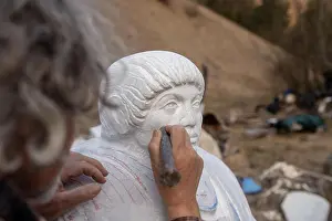 Der Bildhauer arbeitet an seinem Denkmal mit einem Meißel, um Details zu bearbeiten.
