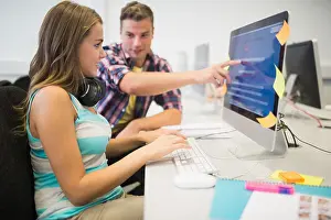 Freundliche Klassenkameraden, die gemeinsam eine Aufgabe im Computerzimmer erledigen.