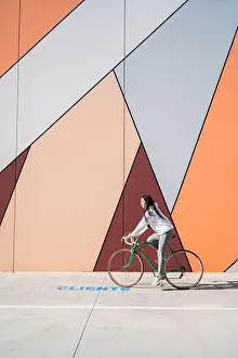 Drucke von Frau des Sports fährt grünen Fahrrad auf der Straße in der Nähe von Wand mit Kunst Straßenkunst Graffiti Drucke: Frau des Sports fährt grünen Fahrrad auf der Straße nahe der Wand mit Kunst.