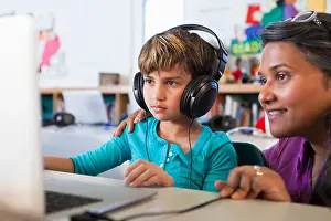 Lehrer hilft Schüler mit Laptop.