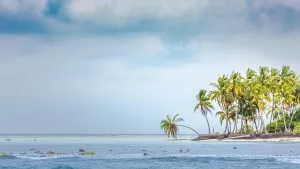 Wolkenreiche tropischer Inselküste oder Ufer, Palmen und Stürmewolken mit welligen Meerwasser oder Ozeanwater. Exotische Zielinsel Küstenlinie