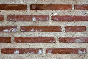 Wand aus roten Backsteinen und Beton.