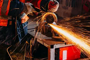 Arbeiter schneidet Metall mit Schleifmaschine in seinem Werkstatt. Funken während des Schleifens von Eisen.