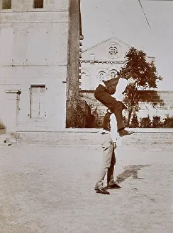 Men In Traditional Clothing Drucke: Two men play leapfrog