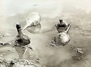 Natural Elements Photography Drucke: Water flasks'. Four empty flasks floating in a pool of water